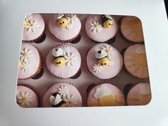 cupcakes decorated with pink frosting and yellow flowers are arranged in a box