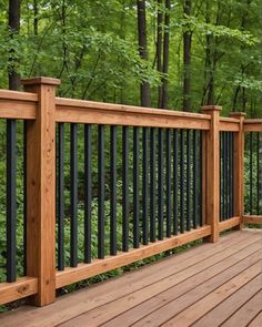 a wooden deck with black iron railings and trees in the background