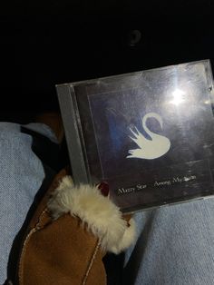 someone is holding up a cd with an image of a swan on it's cover