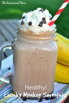 a smoothie with whipped cream and chocolate chips in a mason jar next to bananas