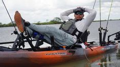 a man sitting in a kayak on the water with fishing rods attached to his feet