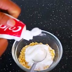 a person is dipping something into a small glass bowl with cereal in it and a coca - cola can