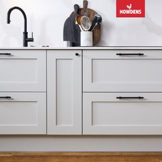 a kitchen with white cabinets and black handles