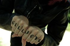 a woman with tattoos on her fingers pointing at the camera while wearing a black leather jacket