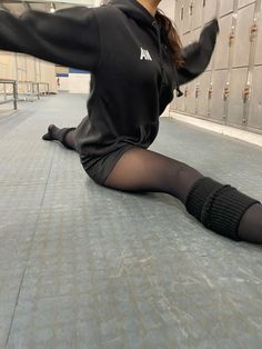 a woman is sitting on the floor with her legs spread out and wearing black tights