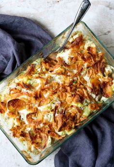 a casserole dish with onions and cheese in it next to a blue napkin