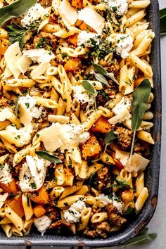 a casserole dish with pasta, cheese and sage leaves on the side is ready to be eaten