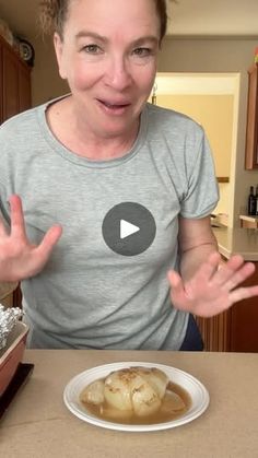 a woman holding her hands out in front of a plate of food on a table