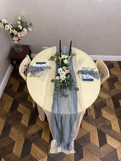 the table is set with flowers and napkins on it, along with place settings