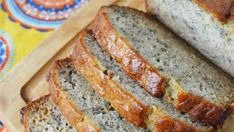 slices of banana bread on a cutting board with a colorful towel in the back ground