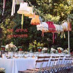 a long table is set up for a party with paper lanterns hanging from the ceiling