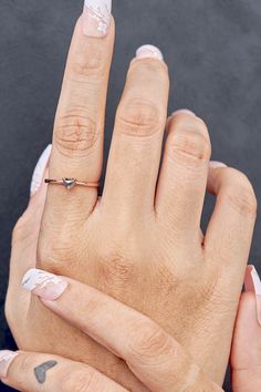 two hands with white and black nail polish holding each other's fingers, one has a diamond ring on it