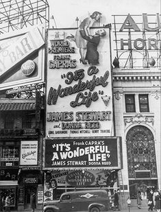 an old black and white photo of the outside of a building with advertisements on it