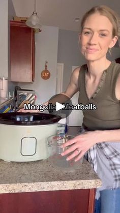 a woman standing in front of a slow cooker with the lid open and her hands out