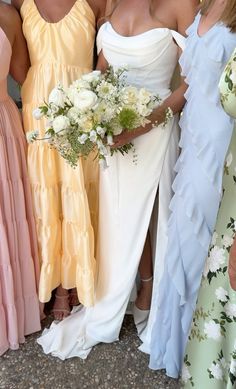 three women in dresses standing next to each other holding bouquets and posing for the camera