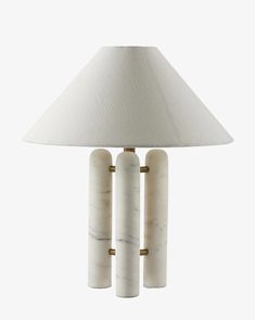 a white lamp with three marble columns on the base and a light shade over it