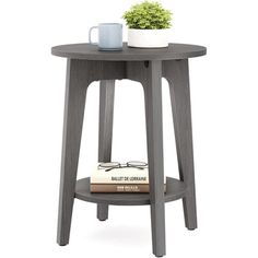 a small table with a book and cup on it, next to a potted plant