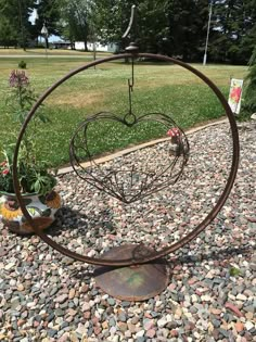 a metal heart shaped planter sitting on top of a gravel covered ground