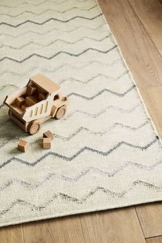 a wooden toy car sitting on top of a rug