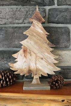 a wooden christmas tree sitting on top of a table next to two pinecones