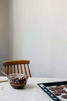 a table topped with chocolate cookies and a bowl of frosting on top of it