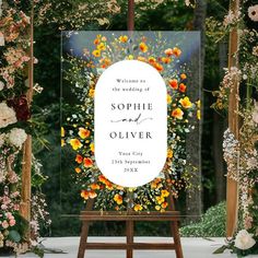 a welcome sign with flowers on it in front of an outdoor wedding ceremony arch that reads, welcome to the wedding of person and person