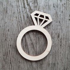 a wooden ring with a diamond cut out of it sitting on a piece of wood