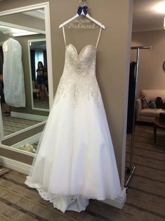 a wedding dress hanging on a hanger in front of a mirror