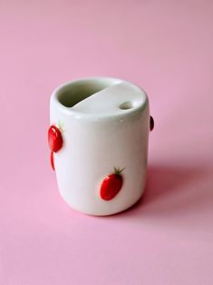 a white vase with two strawberries on the outside and one strawberry on the inside