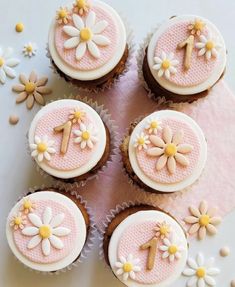 six cupcakes decorated with pink and white icing, daisies and flowers