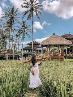 a woman in a white dress is walking through the grass with her arms spread out