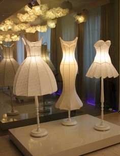 three mannequins with dresses on display in front of a mirror