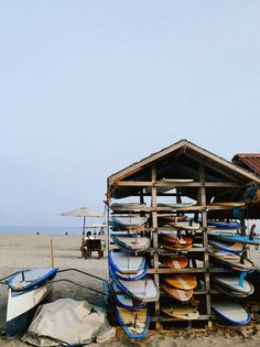 there are many surfboards stacked up on the beach and in front of a building