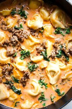 a skillet filled with pasta and meat covered in sauce, garnished with parsley