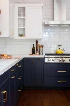 a kitchen with white and blue cabinets, wood flooring and stainless steel stove top oven