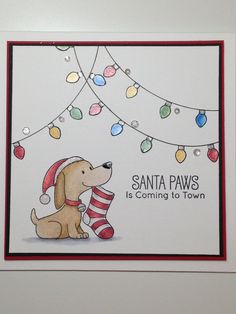 a card with a dog holding a christmas stocking on it's nose and saying santa paws is coming to town