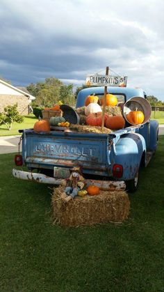 an old blue truck with pumpkins in the back