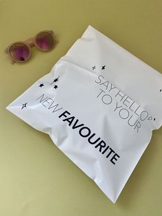 a white bag with the words say hello to your new favorite on it next to sunglasses