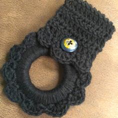 a black knitted object with a button on it's end sitting on the floor