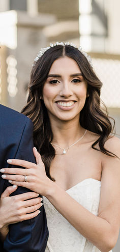 a bride and groom posing for the camera with their arms around each other, smiling