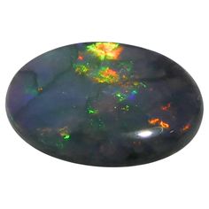 an oval shaped black opal with green and orange highlights on the top, surrounded by white