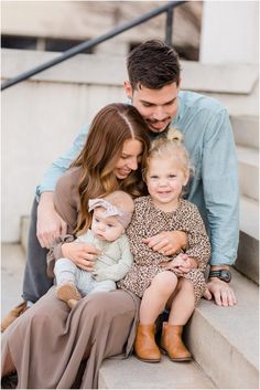 a man, woman and child are sitting on the steps with their arms around each other