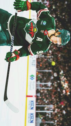 a hockey player in green and white uniform on the ice