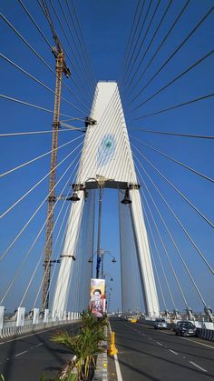 a large white bridge with many wires above it and cars driving on the road below