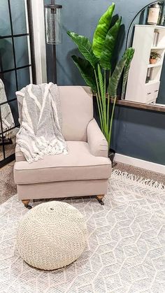 a living room with a chair, ottoman and potted plant on the floor in front of it