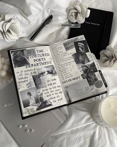 an open book sitting on top of a bed next to a candle and some flowers