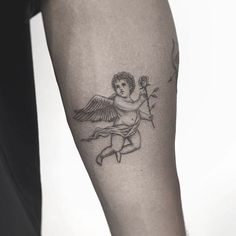 an angel tattoo on the leg of a man with a rose in his left hand