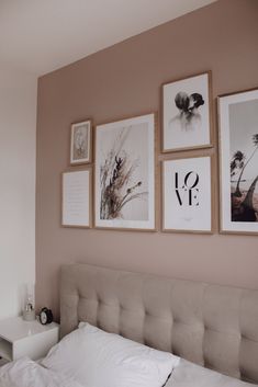 a bed with white sheets and pictures on the wall above it, in a bedroom