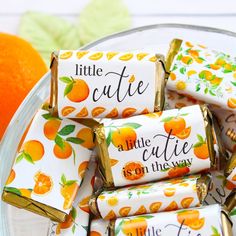 candy wrapped in little cutie oranges on a plate next to an orange and the words, candy not included