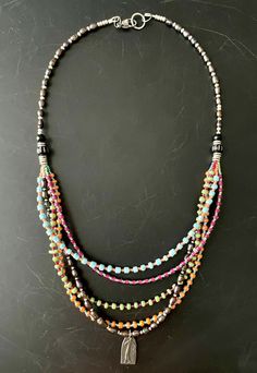 "Stunning black oval shaped cultured pearls are offset with brightly colored glass seed beads in this 5-strand multicolored necklace. A small patina'd charm dangles from the pearl strand and features an abstract figure of a woman. This piece measures approx \" with a silver metal lobster claw clasp and 2\" adjustable jump chain. The bright colors in this necklace are tasteful and nicely balanced by the black pearls. A nice, versatile piece that goes with anything. Perfect gift!" Double Strand Necklace Beaded, Accessories Idea, Pearl Charm Necklace, Black Pearls, Pearl Strand, Double Strand Necklace, Handmade Jewel, Pearl Charms, Glass Seed Beads